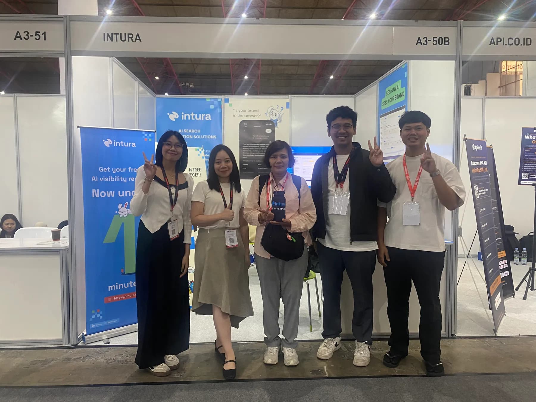 Stand Intura A3-50B di INTI 2026, JIExpo Jakarta, dengan roll-up banner yang menawarkan laporan AI visibility gratis dan stand tetangga A3-51 serta API.CO.ID di kiri-kanan